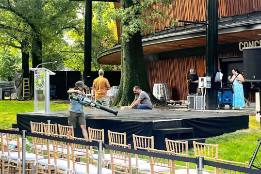 A person uses a leaf blower to dry off an outdoor theater stage